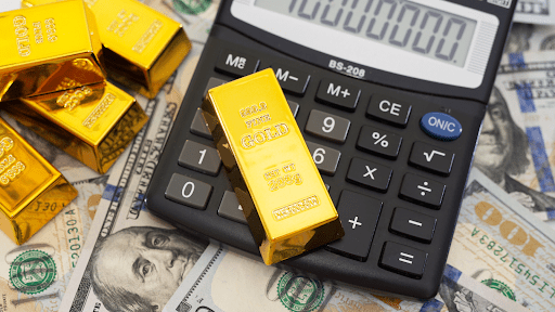 gold bars above cash notes and a calculator