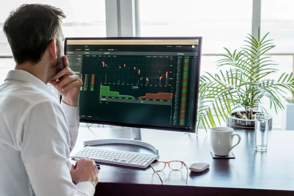 trader analysing trading data shown on a monitor screen